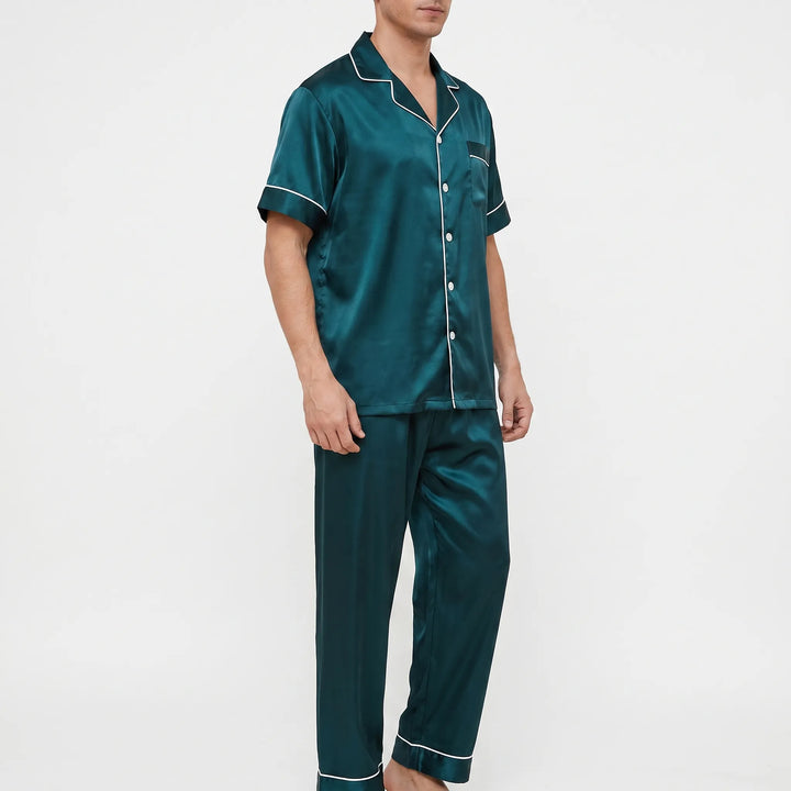 Three-quarter side view of the dark green pajama set, showing the button front, piped pocket, and cuffed pant hems. 4