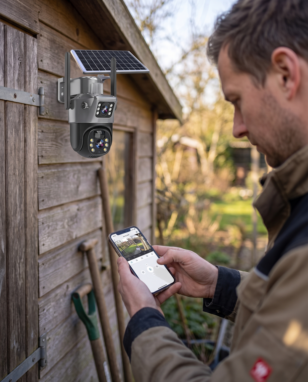Man checking the solar security camera's live view on a smartphone beside a garden shed, another view.