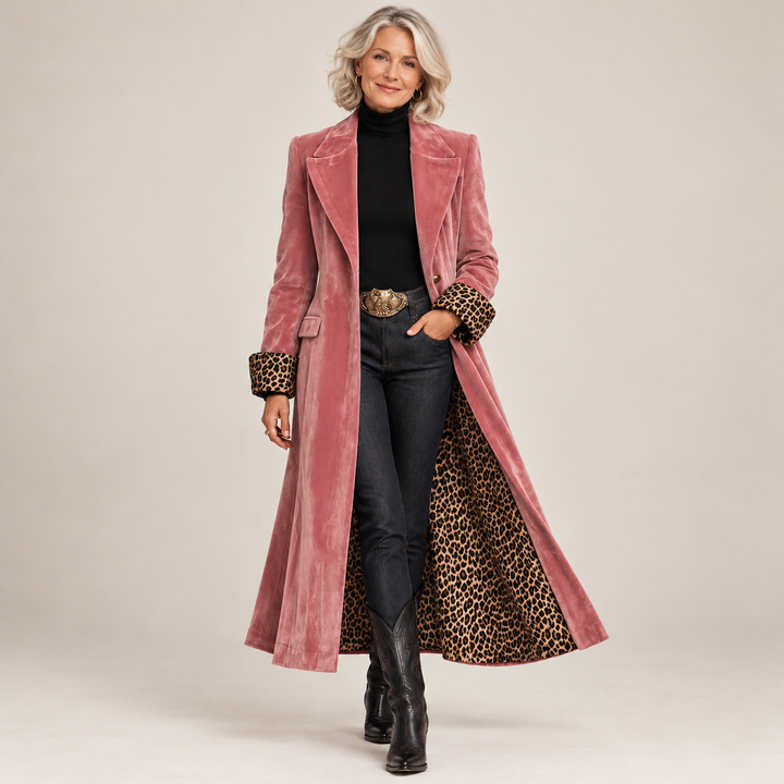 Full-length view of a woman wearing the pink velvet-effect coat open over a black turtleneck, dark jeans and black cowboy boots, leopard lining showing. 1