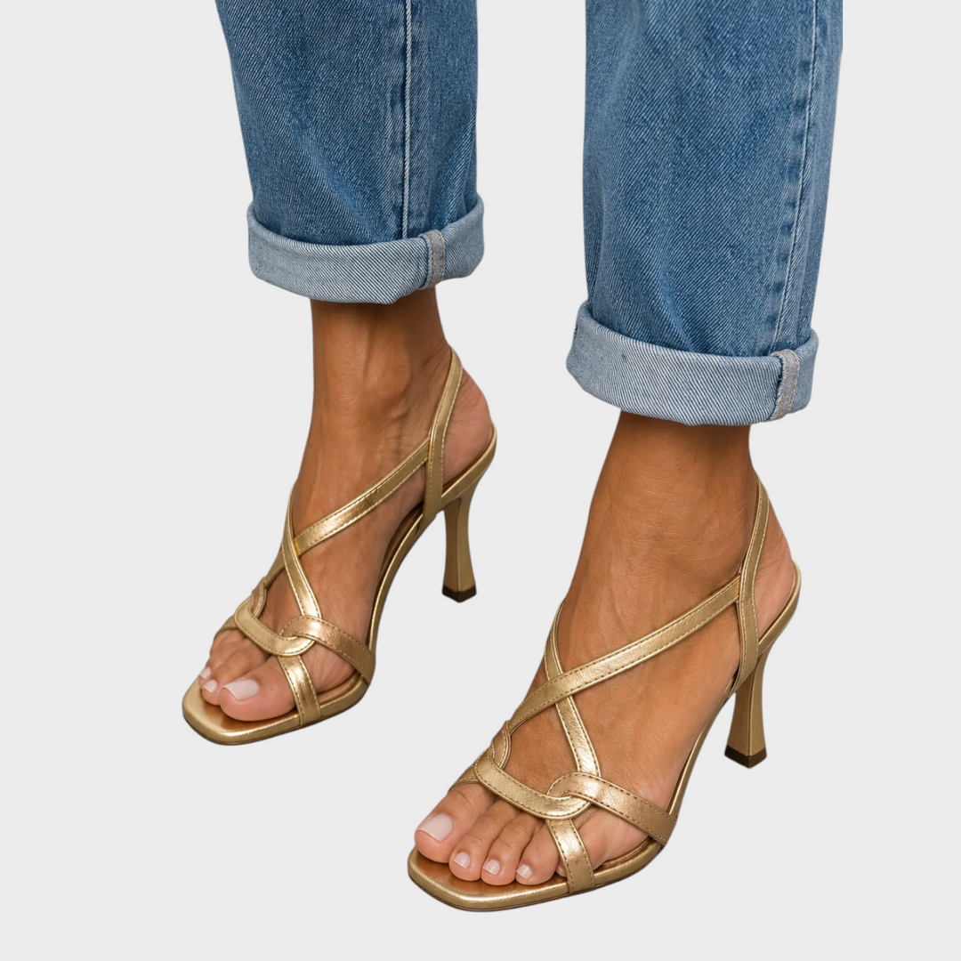 Gold strappy heeled sandals with square toes and cuffed blue jeans, front view. 1