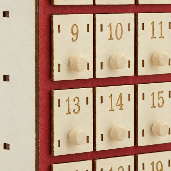 Close-up of numbered drawers 9 to 15 with round wooden knobs, engraved numerals and the red painted wood behind them. 4