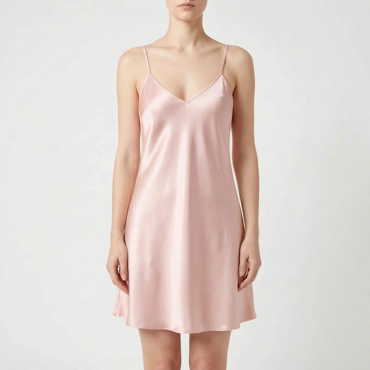 Model wearing the slip nightdress in soft blush pink satin, front view on a light gray background. 7