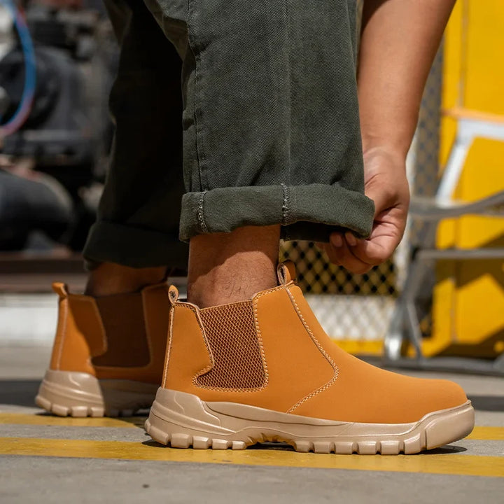 Close-up of a model in tan slip-on boots with mesh side panels, adjusting a rolled pant cuff 3