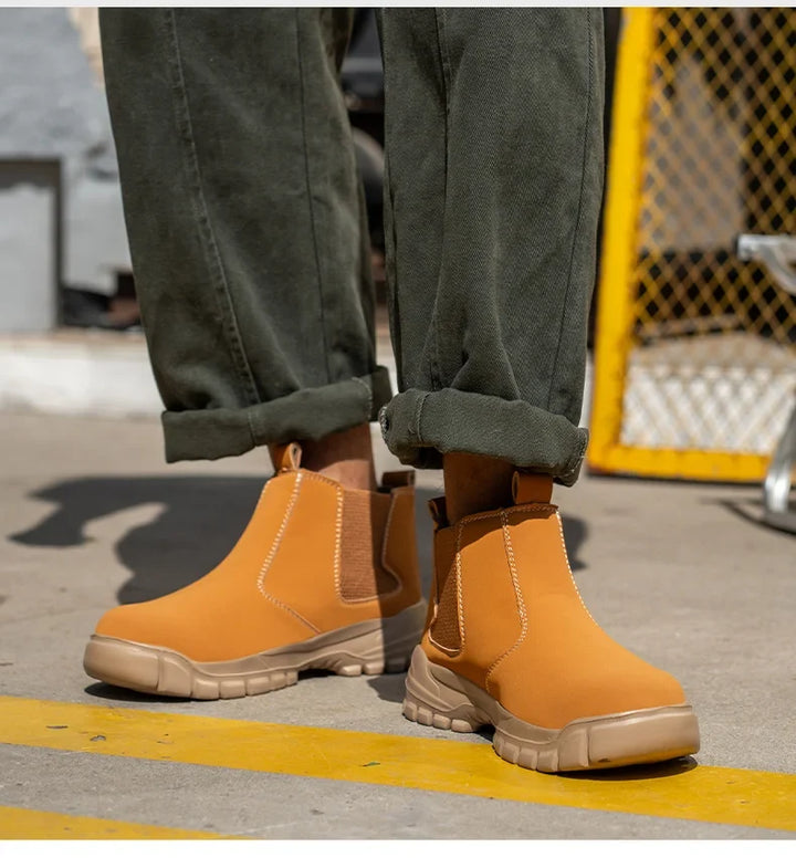 Front view of a model wearing tan slip-on boots with beige lug soles beside a yellow fence 7