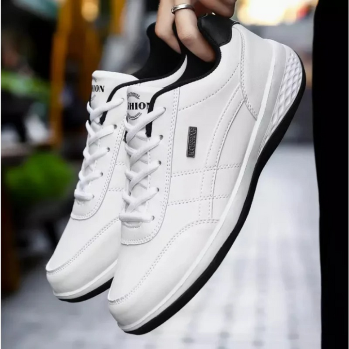 Pair of white leather lace-up sneakers with black heel trim held by hand.