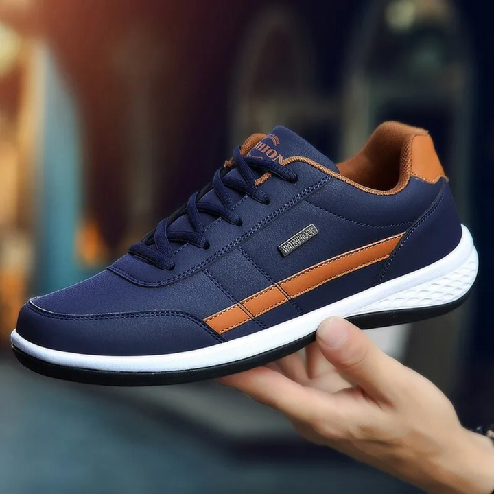Navy blue leather sneaker with a tan side stripe and white textured sole.