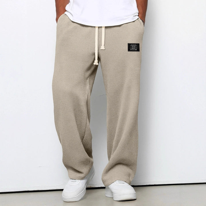 Front view on a model of the wide leg waffle knit pants in beige, with white sneakers 6