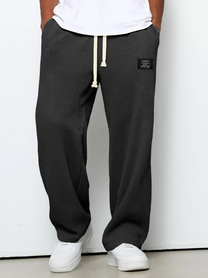 Front view on a model of the wide leg waffle knit pants in dark charcoal gray 1