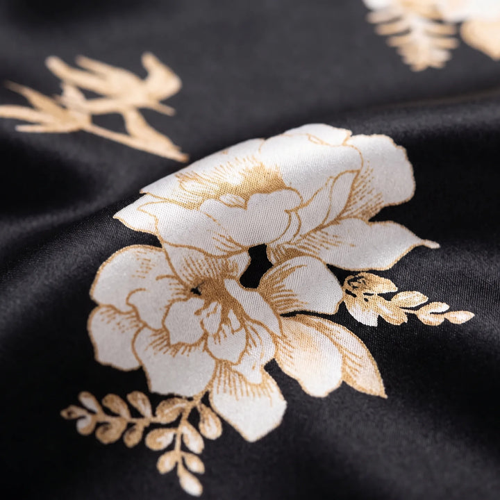 Close-up of the satin fabric in black with a printed cream and gold flower and leaf motif. 5