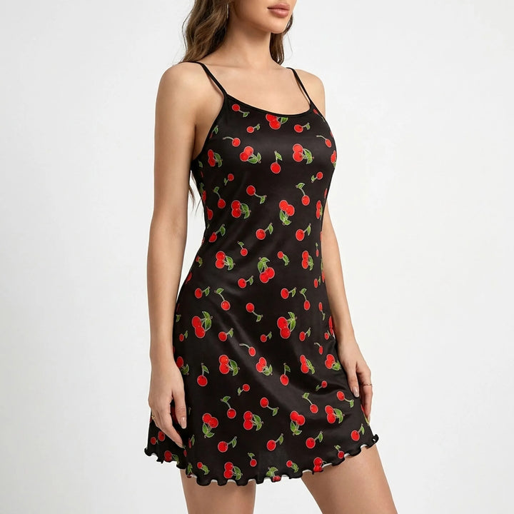 Angled side view of the black chemise with red cherries and green leaves, showing its slim fit through the body and flared hem. 4