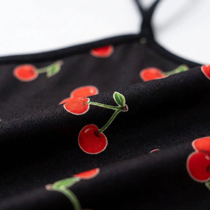 Close-up of the black fabric with a red cherry and green stem print, showing the soft folds and thin strap. 5