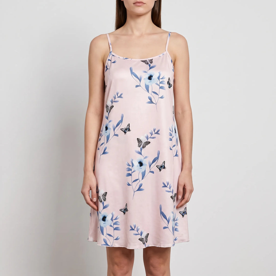 Front view of a model wearing a light pink chemise with blue flowers, leaves and black butterflies, with thin straps and a straight hem. 6