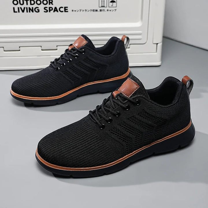 All-black sneakers with black soles and tan trim.