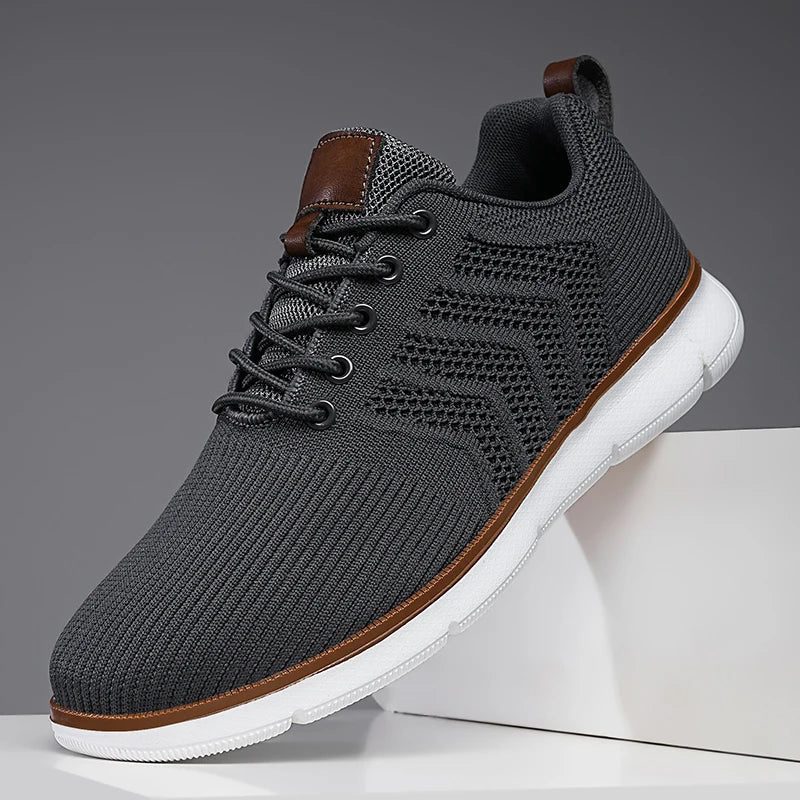 Close-up side view of a dark gray sneaker with a white sole and brown leather tongue patch.