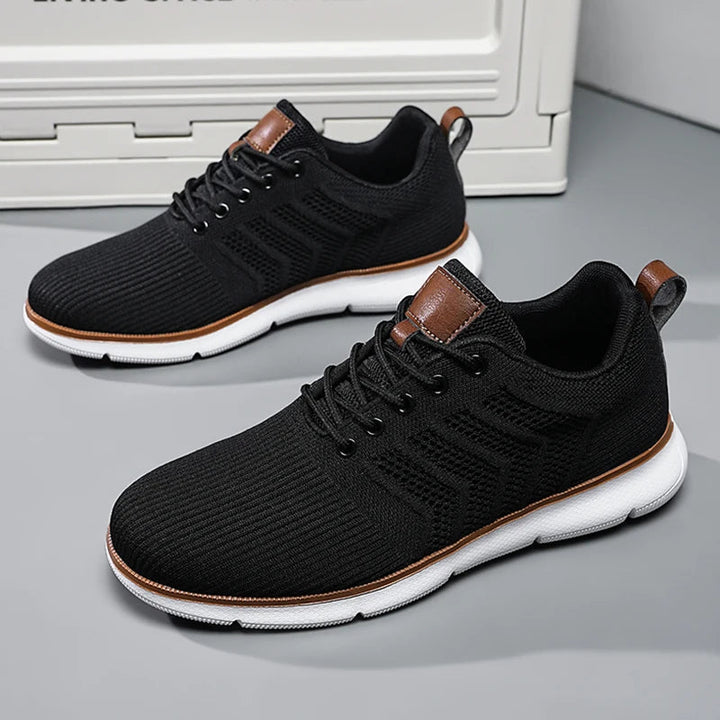 Black lace-up sneakers with white soles and tan leather accents.