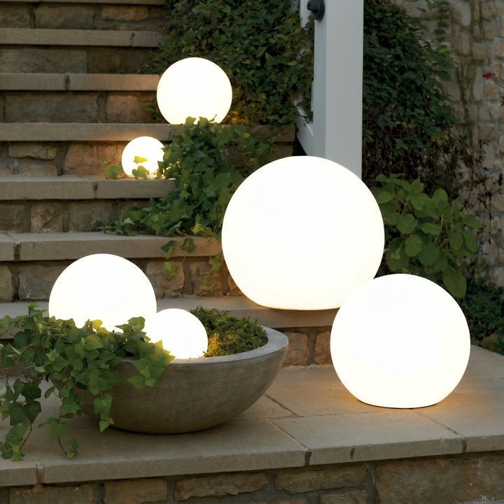 White solar powered orb lights on stone steps and a planter at dusk