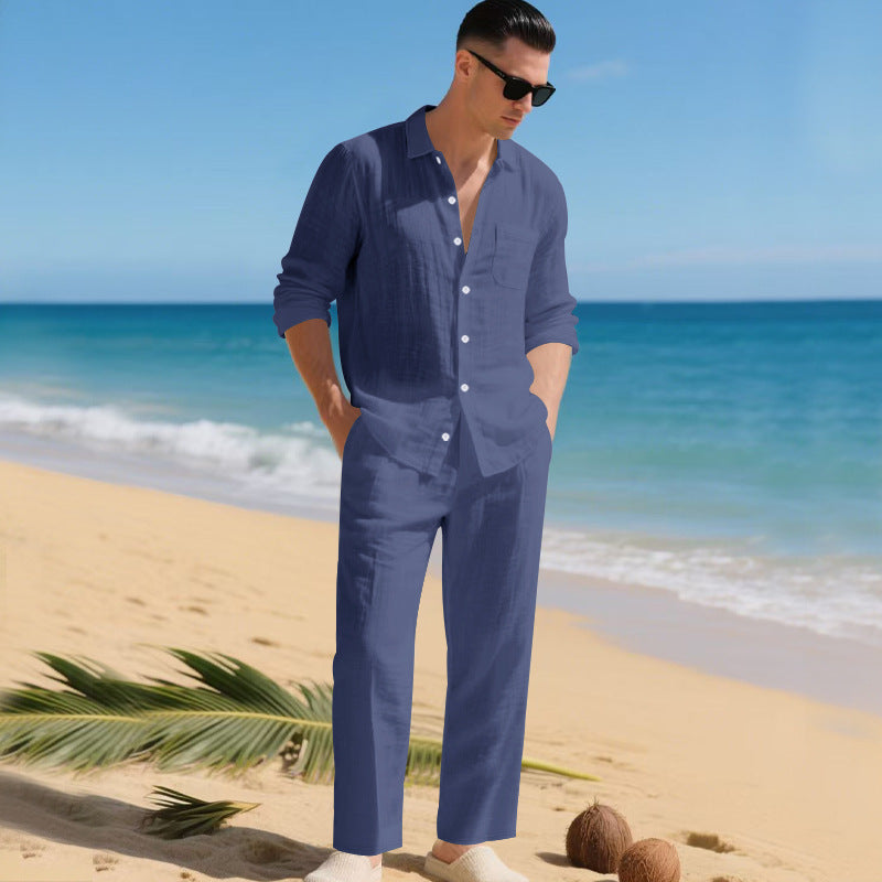 Men's linen shirt and pants set in muted navy blue on a model by the ocean, another view.