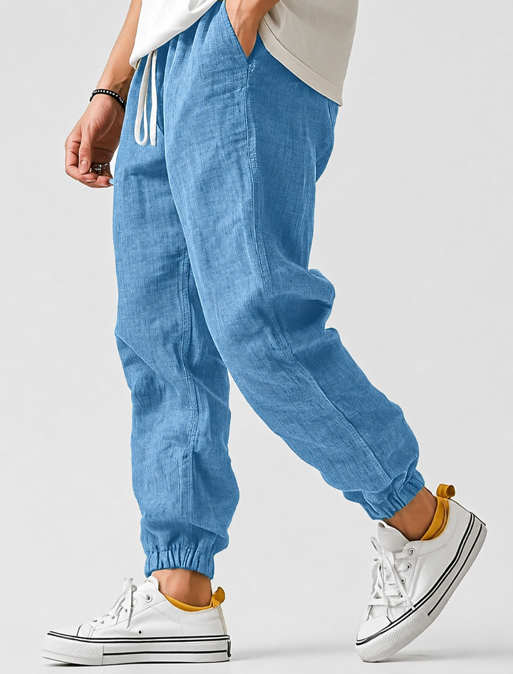 Light blue textured drawstring joggers with elastic ankle cuffs, worn by a model with white sneakers and a white tee.