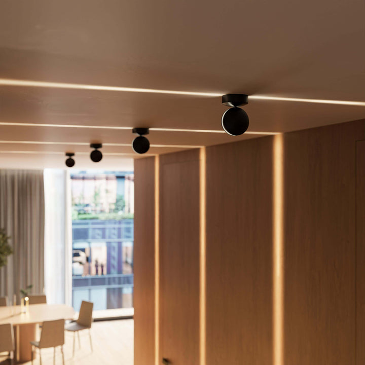 Black LED wall sconce another view showing a row of fixtures sending thin horizontal light lines along the ceiling.