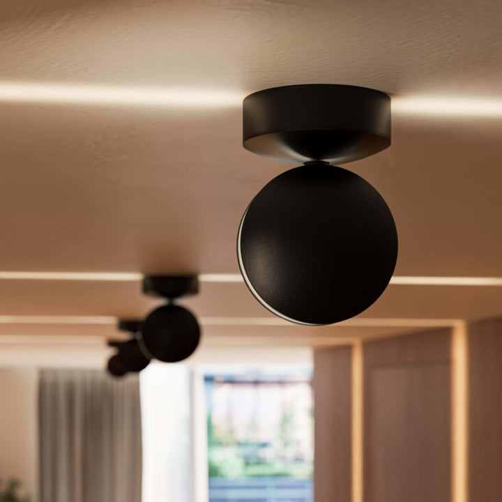 Black LED wall sconce detail showing a round-headed spotlight with thin beams on the ceiling.