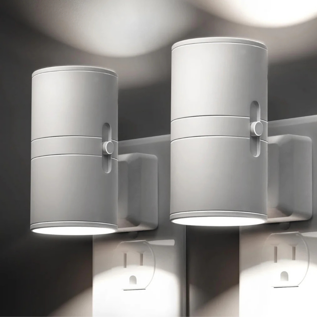 Another view of two white plug-in lamps showing the slider dimmer on the side and cool white light on the wall.