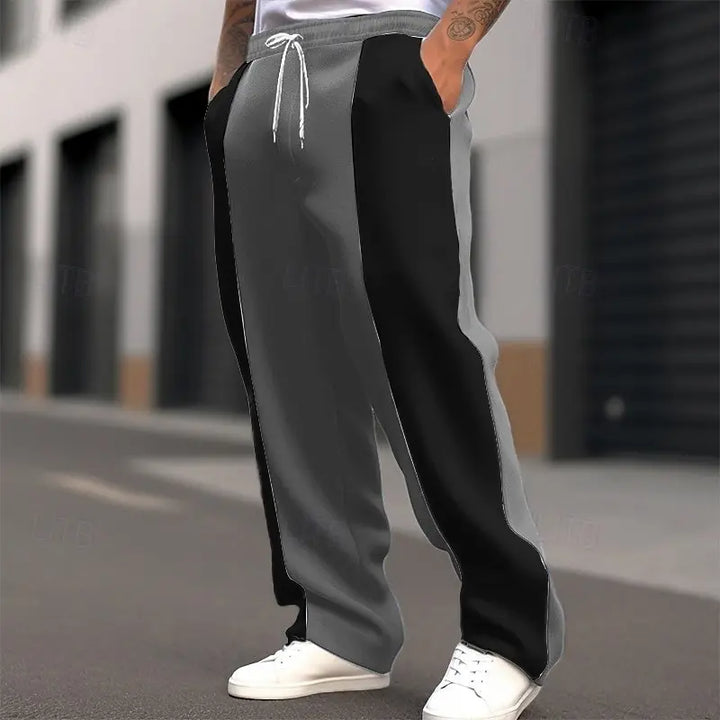 Model on an urban street wearing gray and black color-block sweatpants with a white drawstring and white sneakers 5