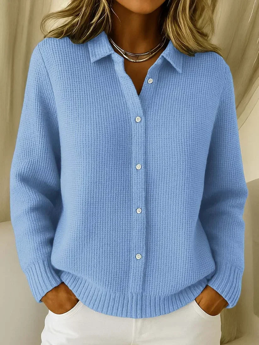 Light blue textured knit polo sweater with collar and white buttons, worn with white pants.