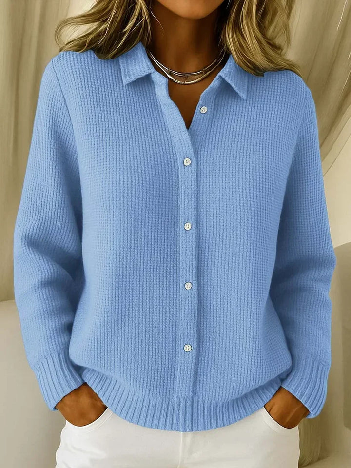 Light blue textured knit polo sweater with collar and white buttons, worn with white pants.