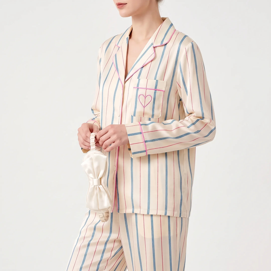 Three-quarter side view of the model holding the cream satin eye mask with a bow, highlighting the pocket's heart embroidery. 4