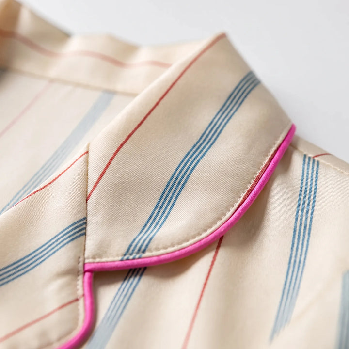 Close-up of the rounded notch collar edged in bright pink piping, showing the fine blue and red stripes on the cream fabric. 5