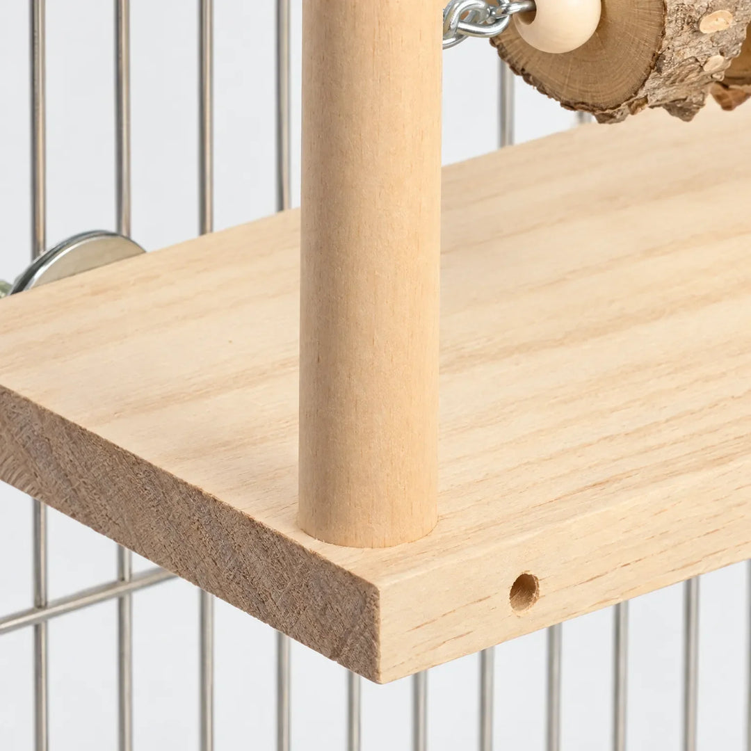 Close-up of the platform's wood grain, a post, a drilled hole, and a metal mounting disc against cage bars. 3