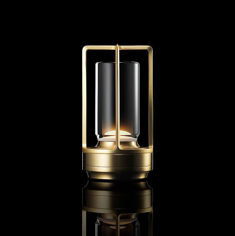 Gold-finish lamp with open metal frame around a clear glass cylinder, glowing softly against a black background with reflection.