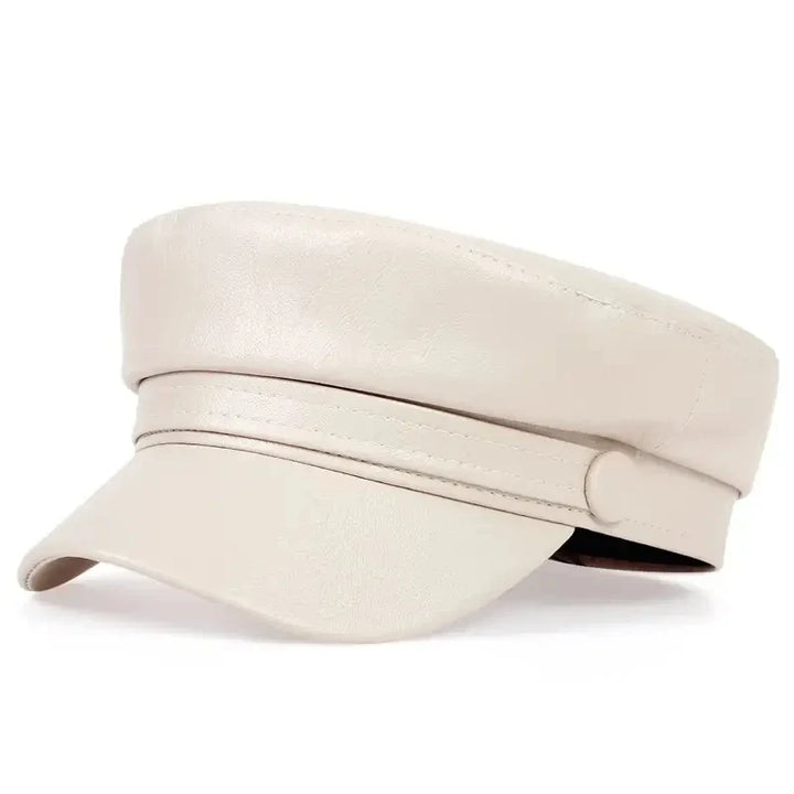 Cream leather-look flat cap with a button strap, shown at a three-quarter angle 11