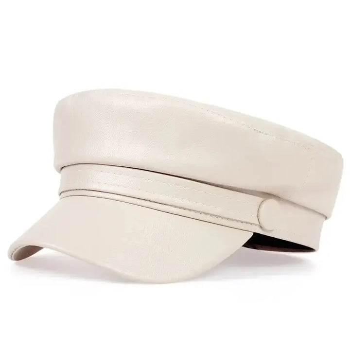 Cream leather-look flat cap with a button strap, shown at a three-quarter angle 17