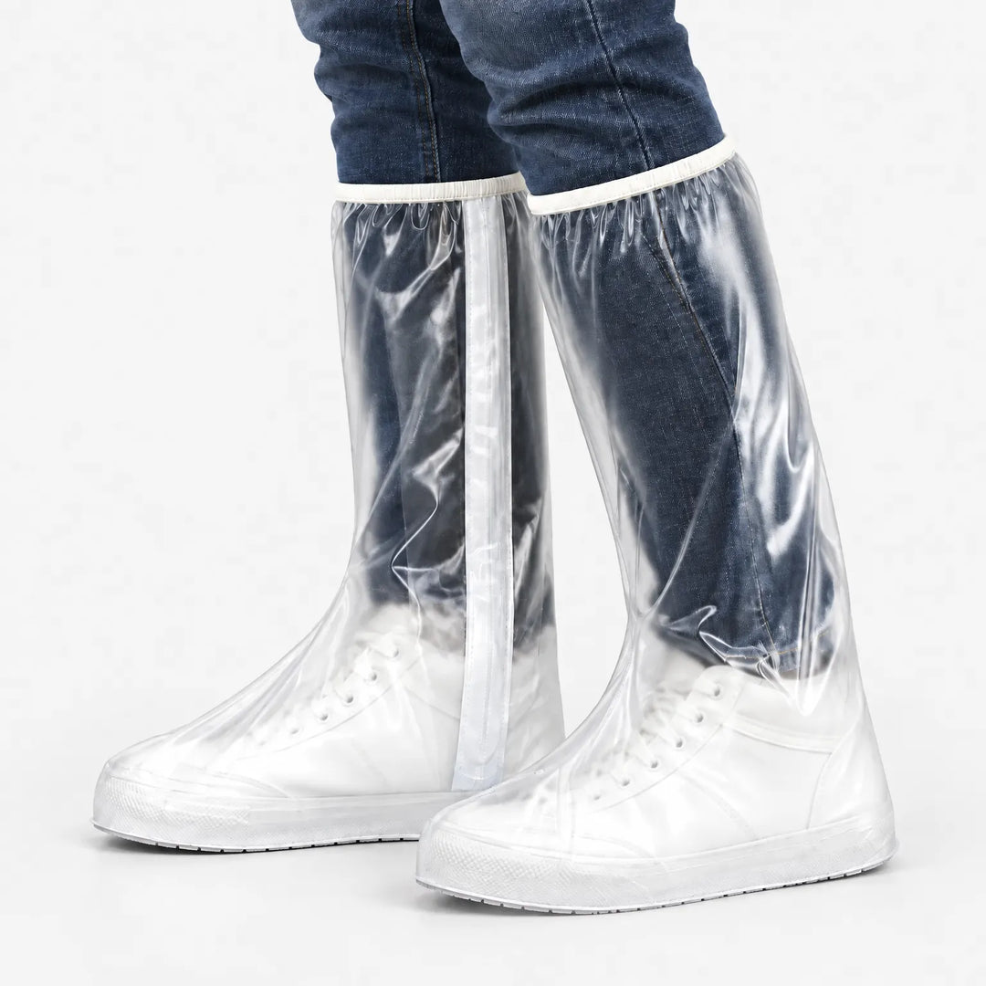 Studio side view of clear tall overshoes with a white zipper strip, worn over white sneakers and rolled jeans on a plain background. 5
