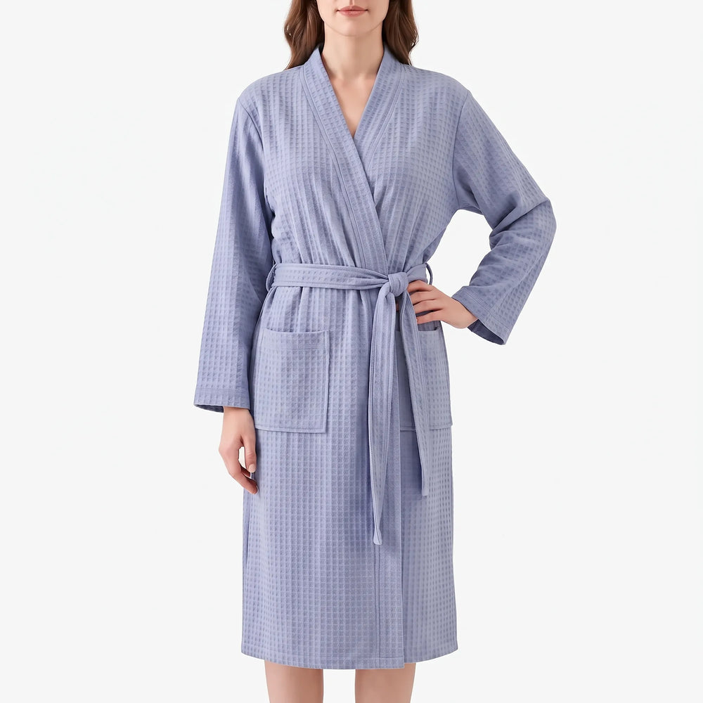 Front view of a model in the lavender-blue waffle-weave robe with shawl collar, tied belt, patch pockets and one hand on hip. 2