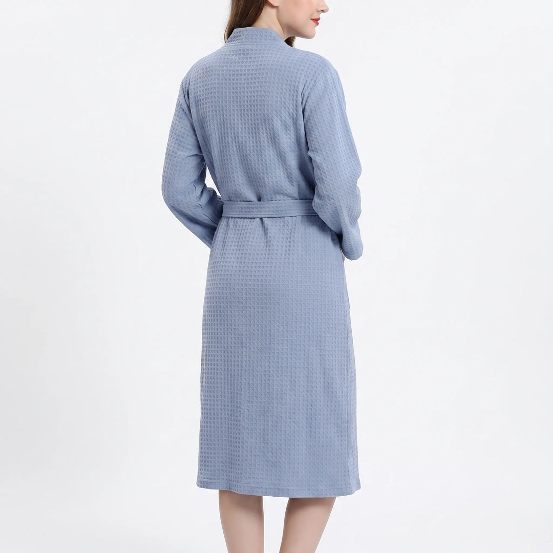 Back view of a model in the blue waffle-weave robe, showing the textured back panel, sleeves and belt wrapped around the waist. 3