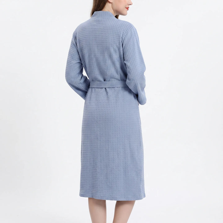 Back view of a model in the blue waffle-weave robe, showing the textured back panel, sleeves and belt wrapped around the waist. 3
