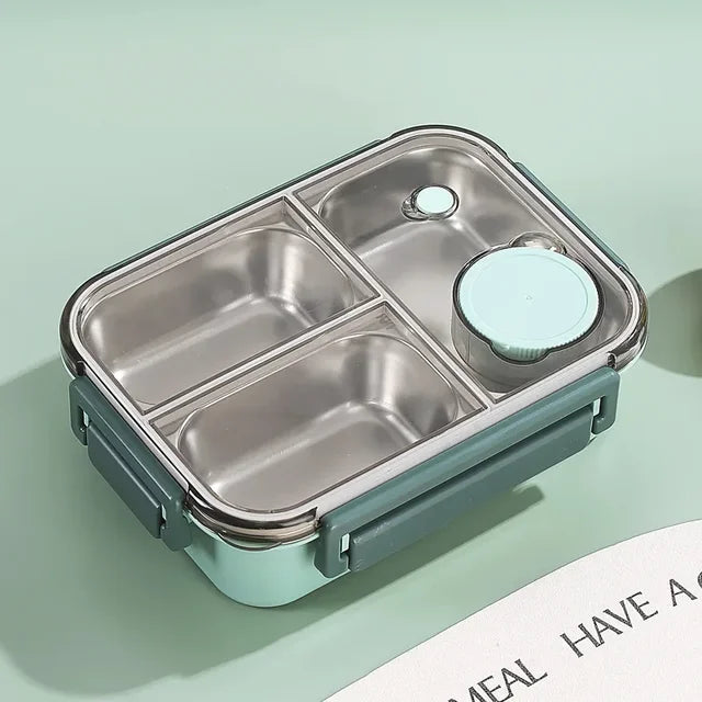 Top view of the mint green container with empty steel compartments, a round sauce cup, and a clear lid on a green background.