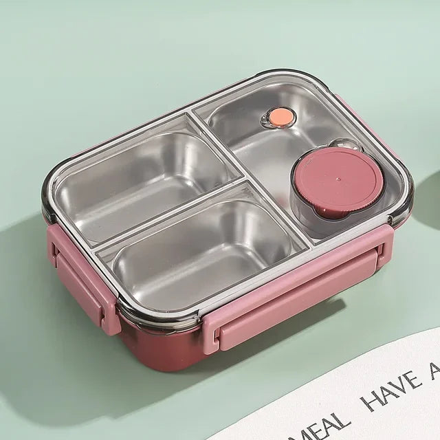 Top view of the pink container with empty steel compartments, a pink sauce cup and a clear lid on a green background.