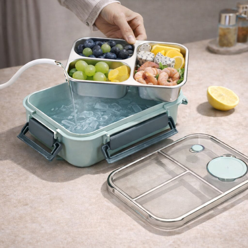 detail of the steel food tray, filled with berries, grapes and shrimp, out of a mint base holding ice water, lid beside it.