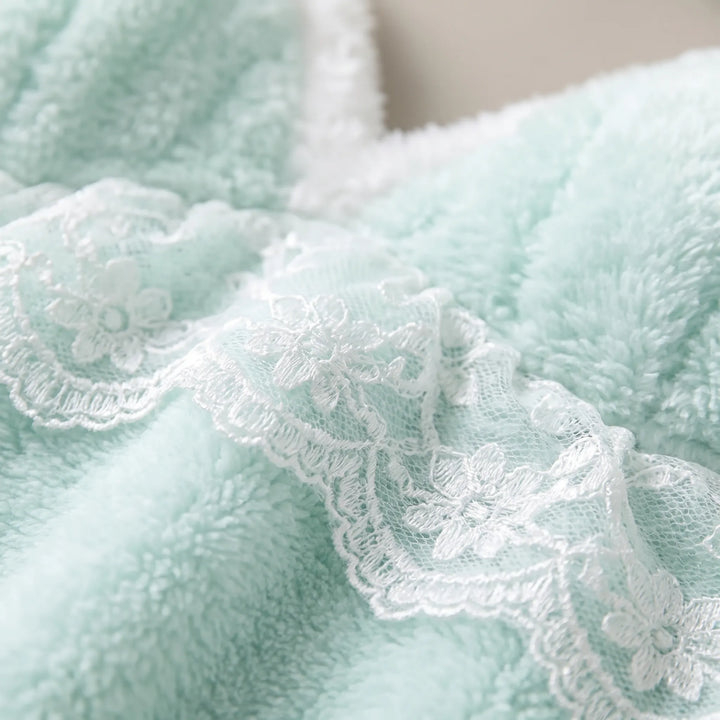 Close-up of the soft mint fleece fabric with white floral lace trim and a fluffy white edge. 5