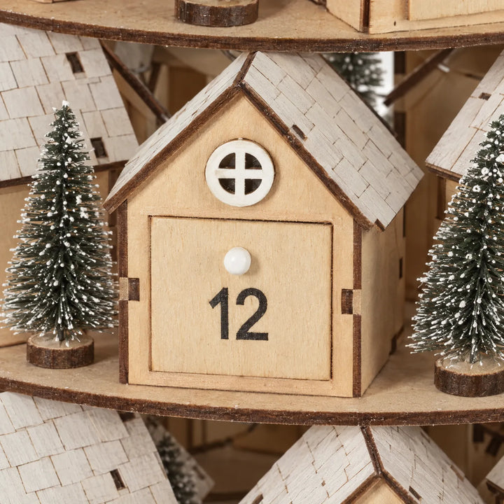 Close-up of one wooden house with a round white window, small drawer door with knob, and frosted trees beside it. 3