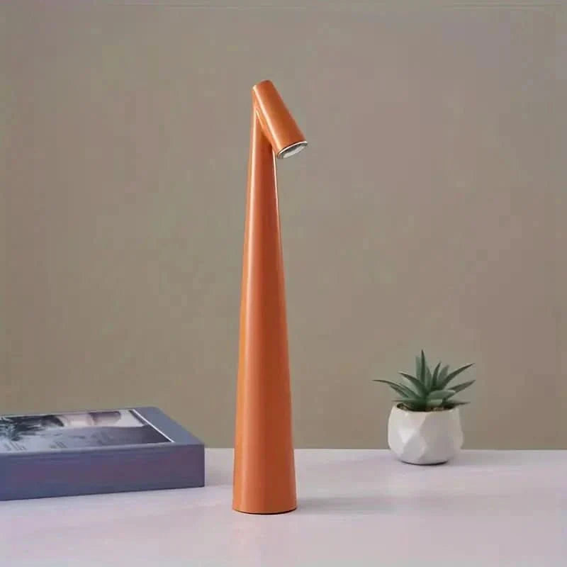 Orange cone-shaped lamp with an angled head standing on a white tabletop beside a small potted succulent and a blue book. 23