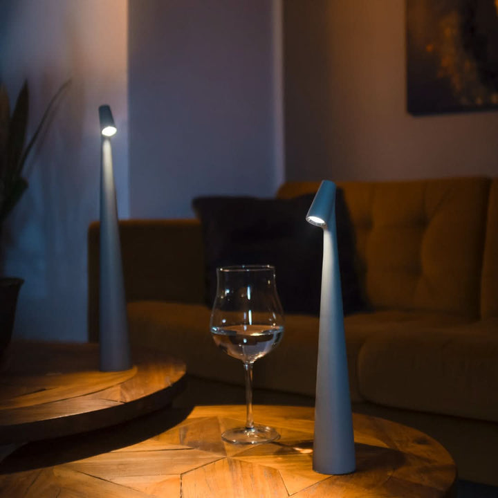 Two gray lamps glowing on round wooden coffee tables, with a wine glass in front of a mustard sofa. 6