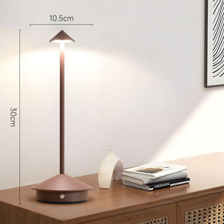 Brown lamp lit on a wooden sideboard with height and width dimension lines beside a vase and books.