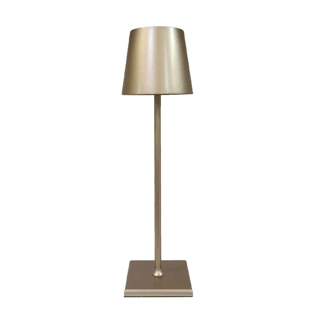 Gold lamp with a tapered shade, slim stem and square base on a white background.