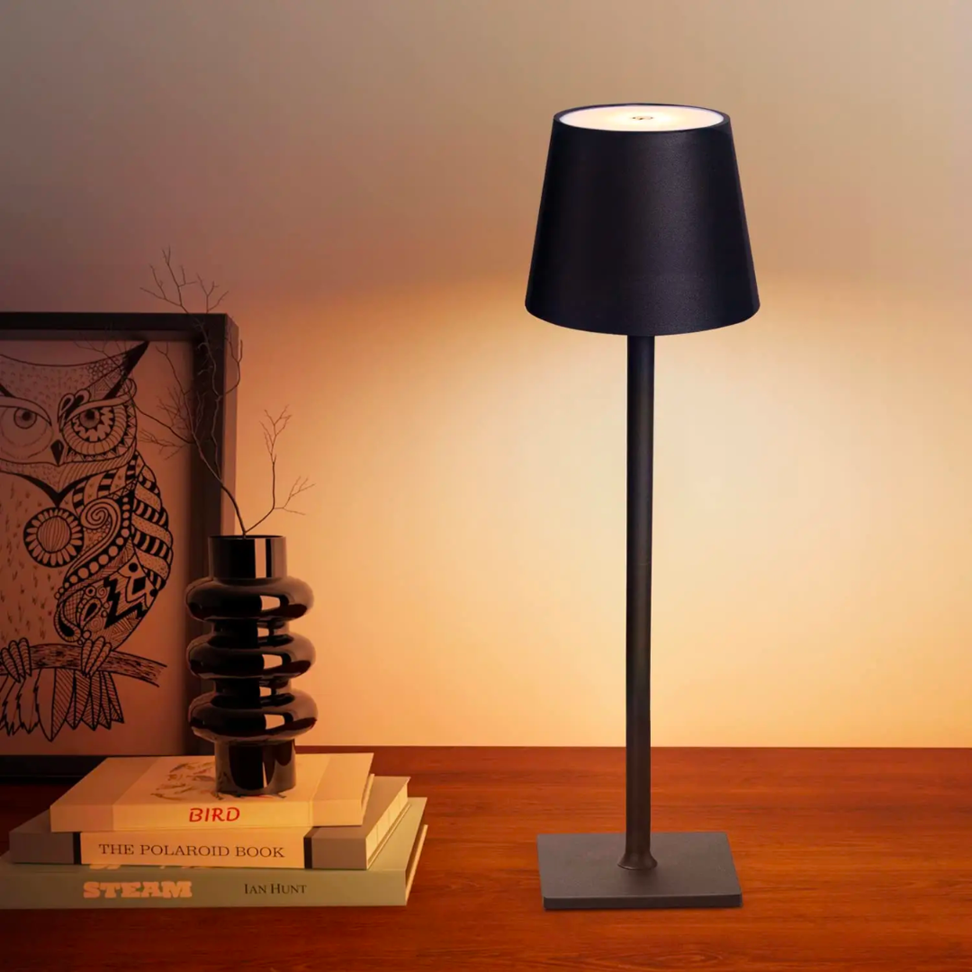 Black cordless table lamp with a tapered shade and square base on a wooden desk.
