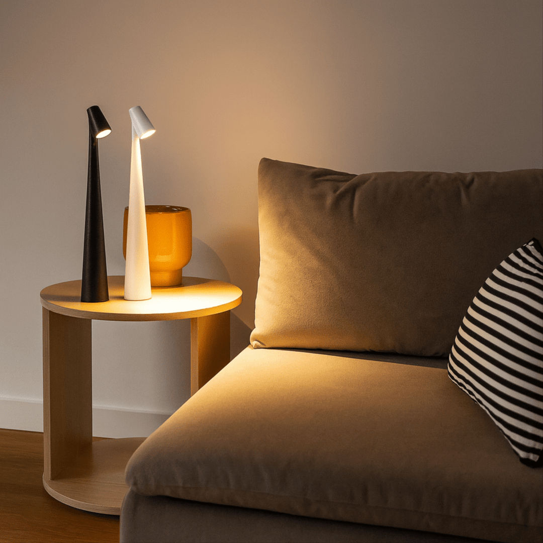 Red cordless table lamps glowing on a round wooden side table next to an amber vase.