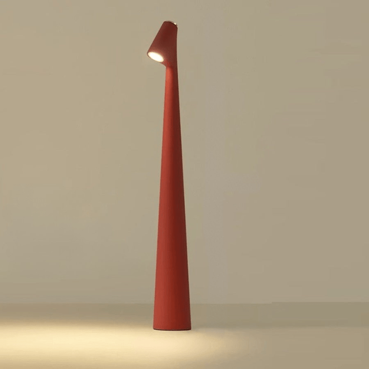 Red cordless table lamp with a slim tapered shape and angled head, glowing warm white.